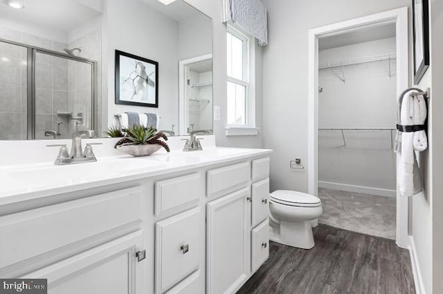 bathroom with a shower with shower door, vanity, wood-type flooring, and toilet