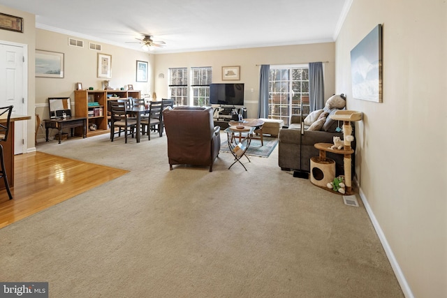 carpeted living room with ceiling fan and ornamental molding