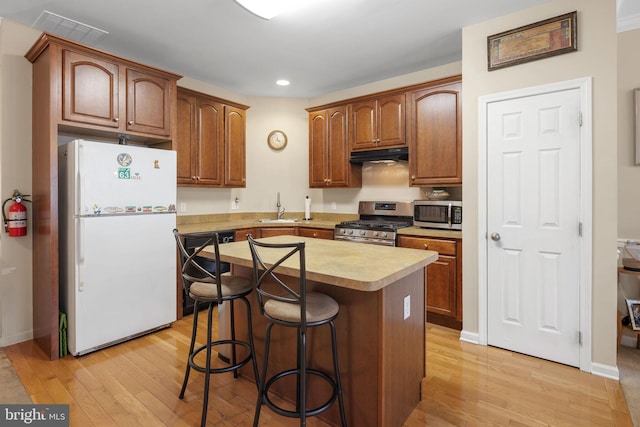 kitchen featuring a center island, stainless steel appliances, light hardwood / wood-style floors, sink, and a breakfast bar area