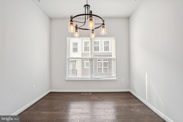 unfurnished dining area with dark hardwood / wood-style floors and a notable chandelier