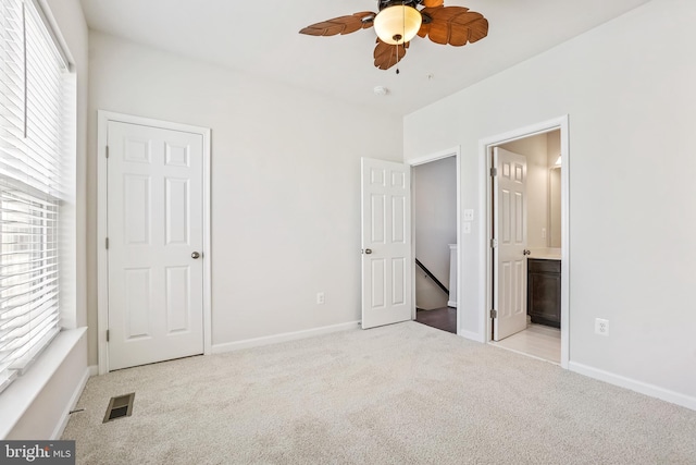 unfurnished bedroom with ensuite bathroom, light carpet, and ceiling fan