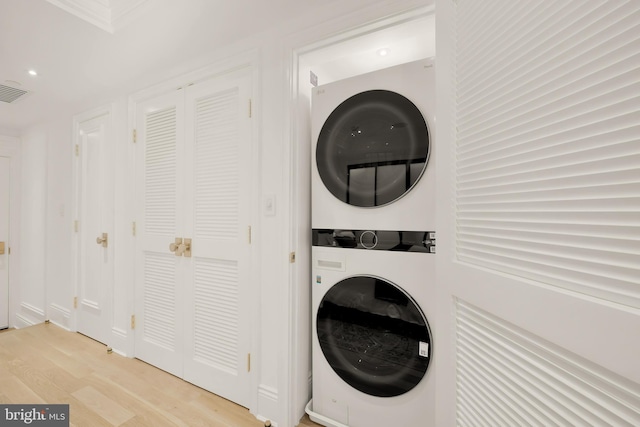 laundry room with stacked washer and dryer and light hardwood / wood-style floors