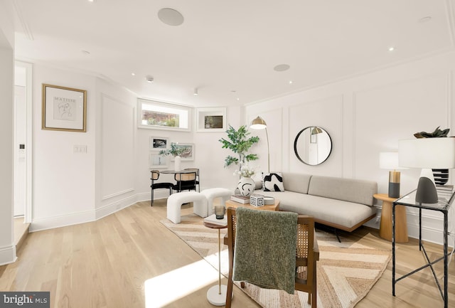 living room with ornamental molding and light hardwood / wood-style flooring