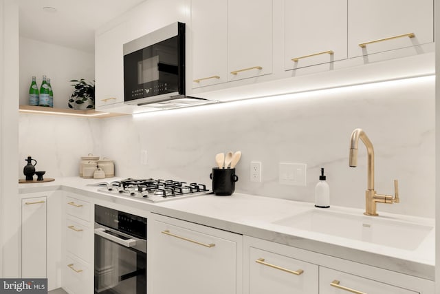 kitchen featuring backsplash, stainless steel gas stovetop, sink, white cabinetry, and wall oven