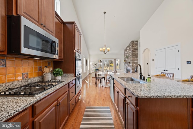 kitchen featuring light wood-style flooring, a sink, appliances with stainless steel finishes, decorative light fixtures, and an inviting chandelier