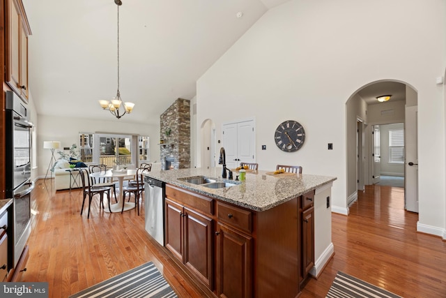 kitchen with a chandelier, stainless steel appliances, a sink, light wood-type flooring, and decorative light fixtures