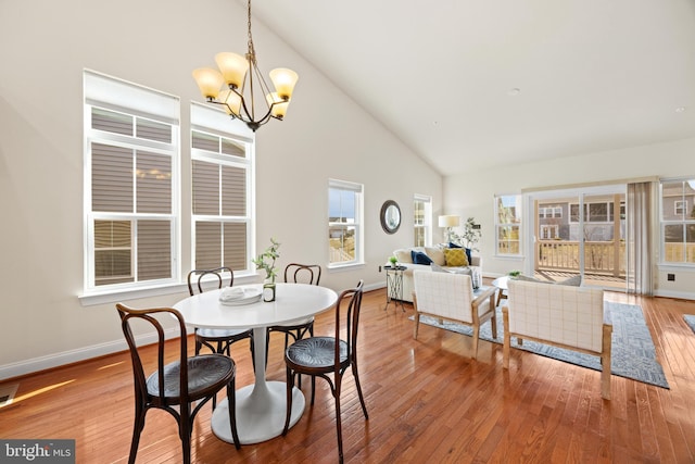 dining space with a chandelier, high vaulted ceiling, hardwood / wood-style flooring, visible vents, and baseboards