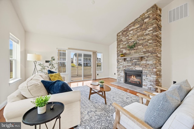 living area featuring baseboards, a fireplace, visible vents, and wood finished floors