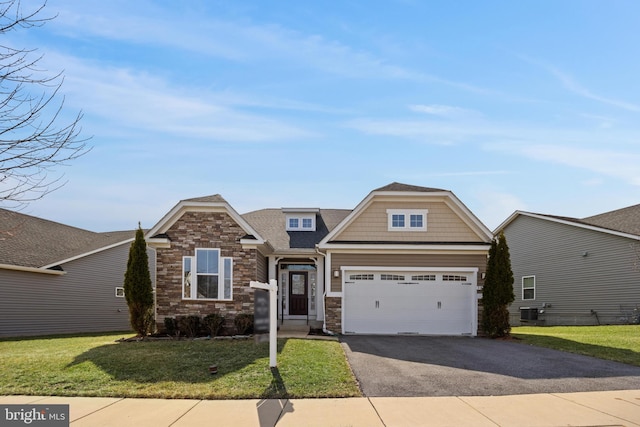 craftsman-style house featuring a garage, stone siding, aphalt driveway, and a front yard