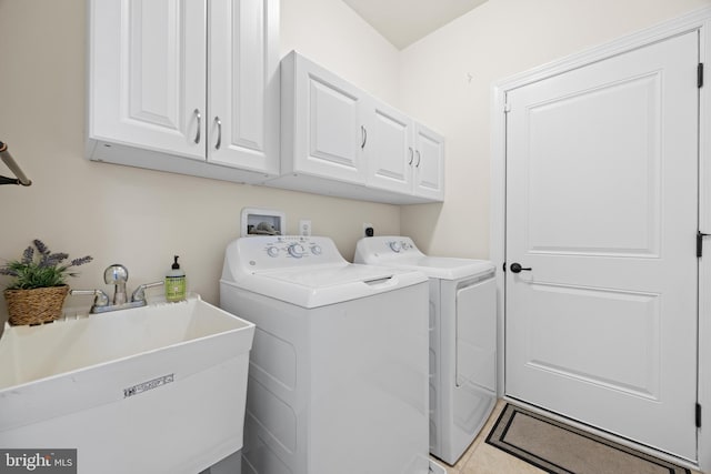 clothes washing area with cabinet space, washer and clothes dryer, and a sink