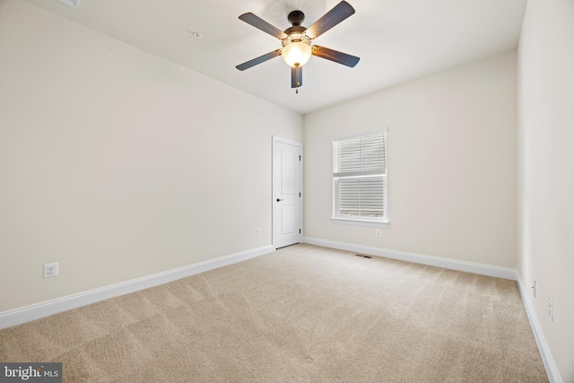 spare room with baseboards, ceiling fan, and light colored carpet