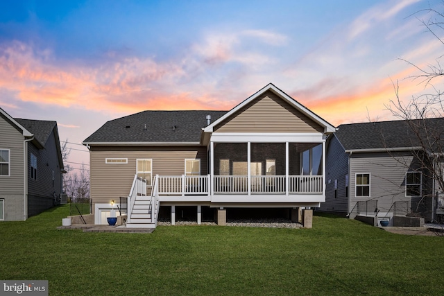 back of property at dusk featuring a shingled roof, a lawn, cooling unit, and a sunroom