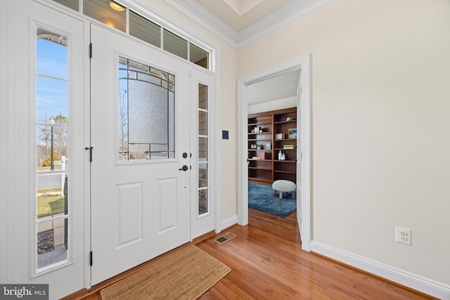 entrance foyer featuring light wood-style floors, baseboards, visible vents, and ornamental molding