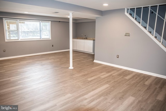 basement with sink and light hardwood / wood-style flooring