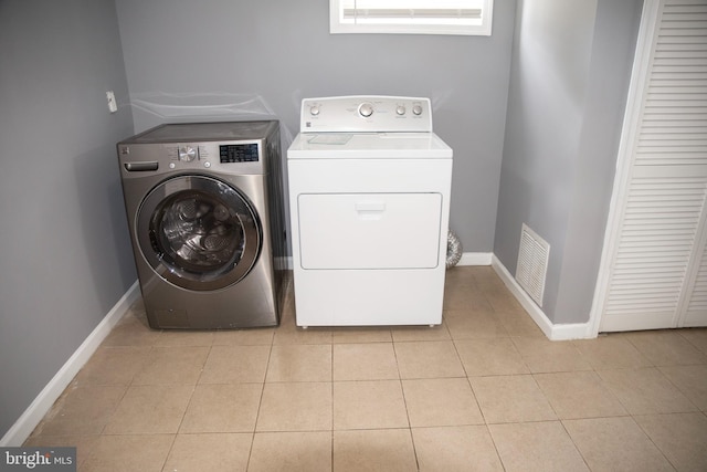 laundry room with light tile patterned flooring and washing machine and clothes dryer