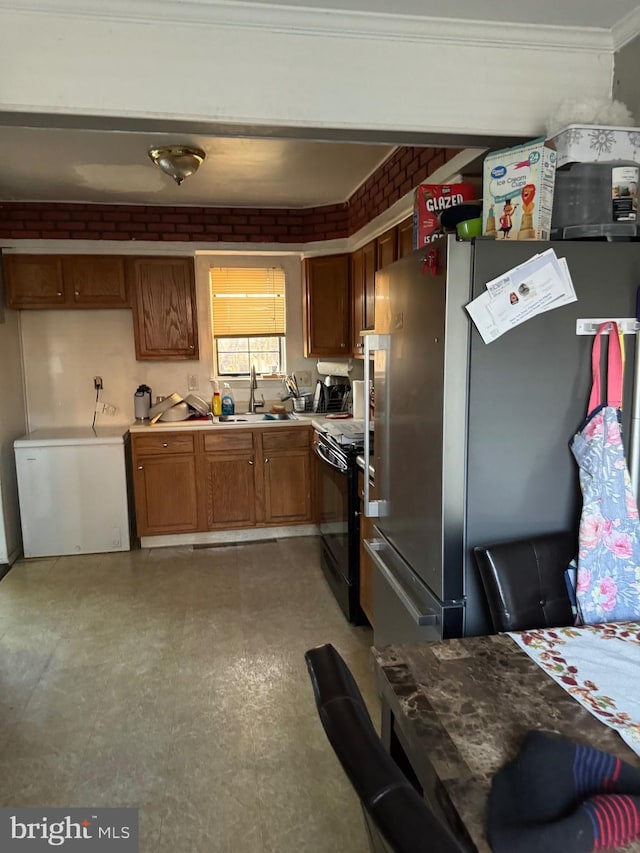 kitchen with refrigerator, electric range, sink, stainless steel fridge, and brick wall