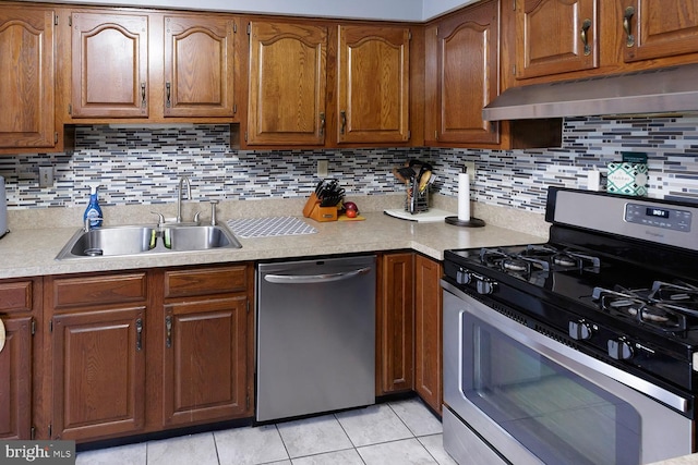 kitchen with light tile patterned floors, backsplash, appliances with stainless steel finishes, and sink