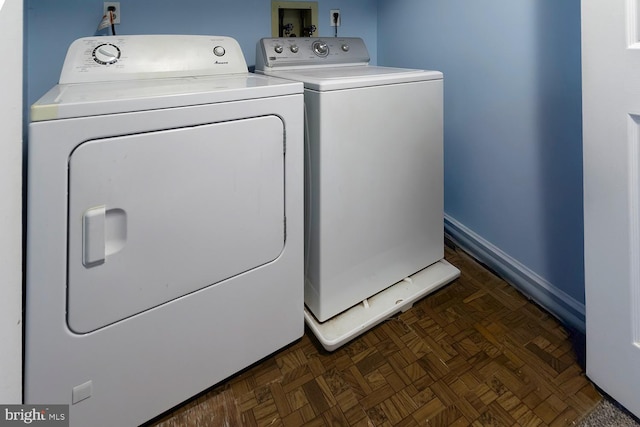 washroom featuring washing machine and dryer and dark parquet flooring