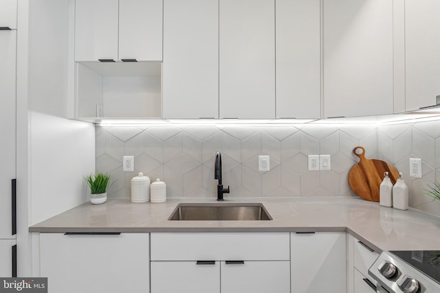 kitchen with white cabinets, decorative backsplash, sink, and light stone counters