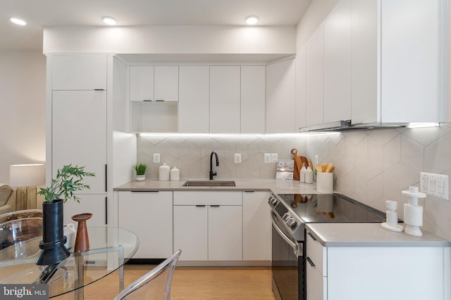 kitchen featuring tasteful backsplash, stainless steel electric range oven, sink, and white cabinetry