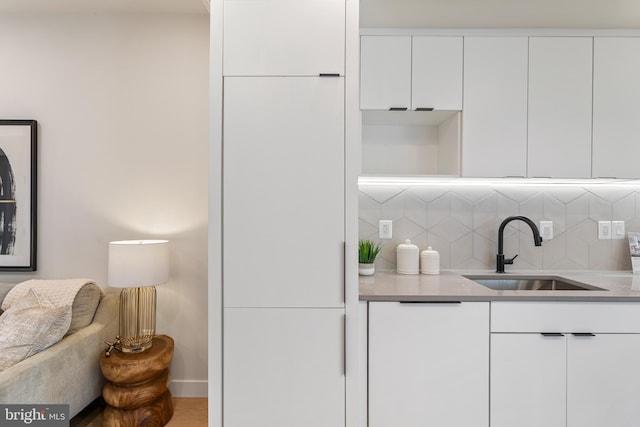 kitchen with white cabinetry, decorative backsplash, and sink