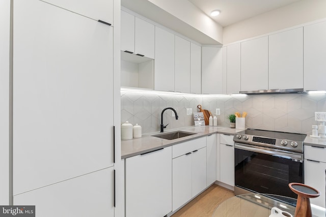 kitchen featuring light hardwood / wood-style floors, stainless steel electric range oven, backsplash, white cabinets, and sink