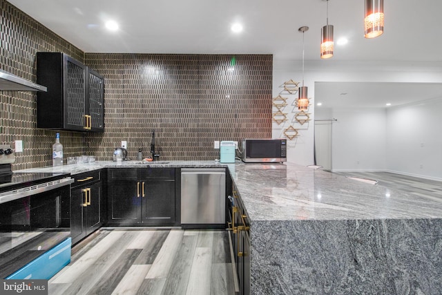 kitchen with sink, light stone counters, decorative light fixtures, stainless steel appliances, and decorative backsplash