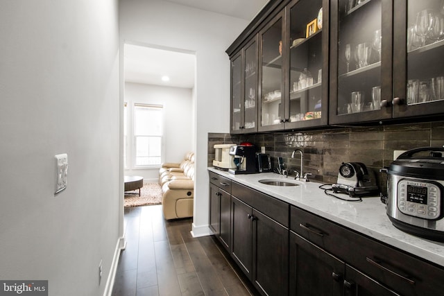 bar featuring tasteful backsplash, sink, dark brown cabinets, and light stone countertops