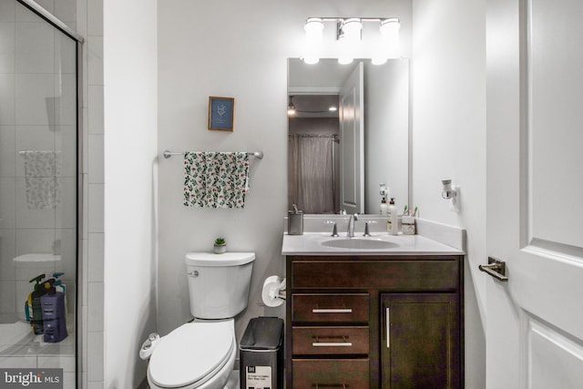 bathroom with a shower with door, vanity, and toilet