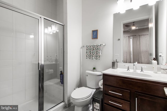 bathroom featuring vanity, a shower with door, and toilet