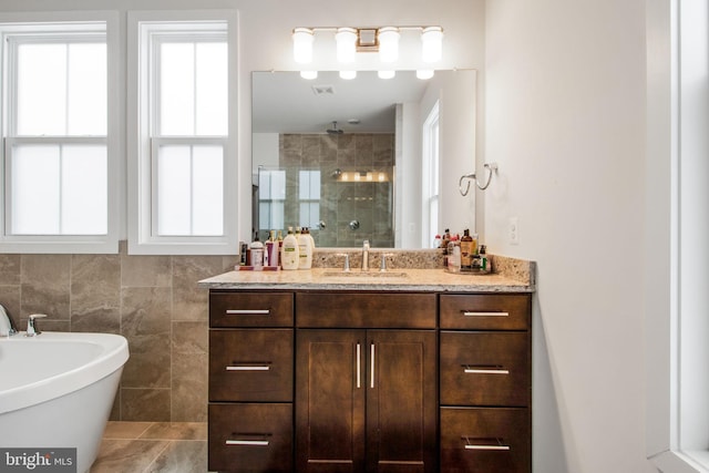 bathroom featuring vanity, plus walk in shower, and tile walls