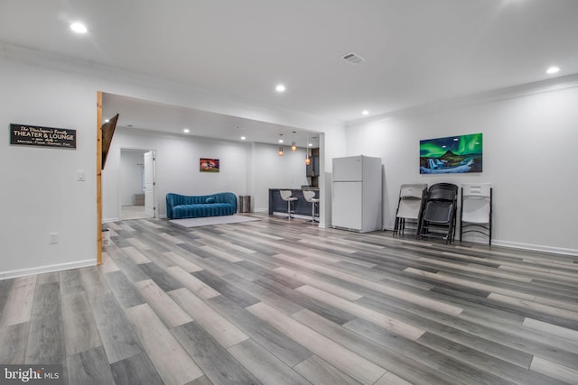 living room featuring crown molding and light hardwood / wood-style flooring