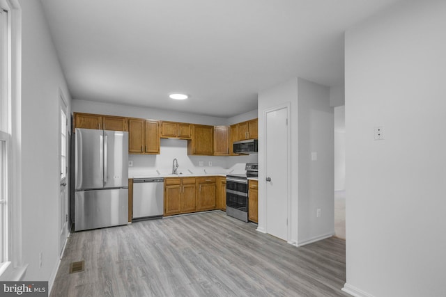 kitchen with sink, appliances with stainless steel finishes, and light wood-type flooring