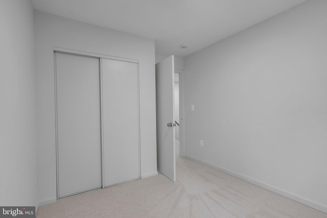 unfurnished bedroom with a closet and light colored carpet