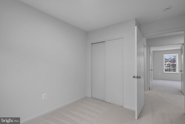 unfurnished bedroom featuring light carpet and a closet