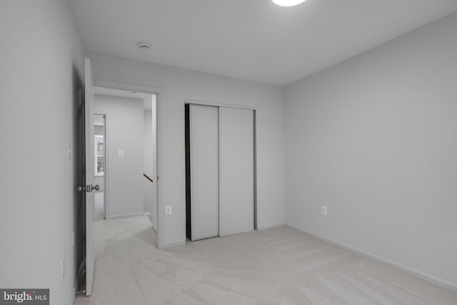 unfurnished bedroom with a closet and light colored carpet