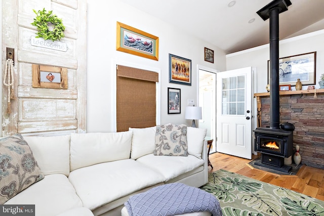 living room featuring hardwood / wood-style flooring, vaulted ceiling, and a wood stove