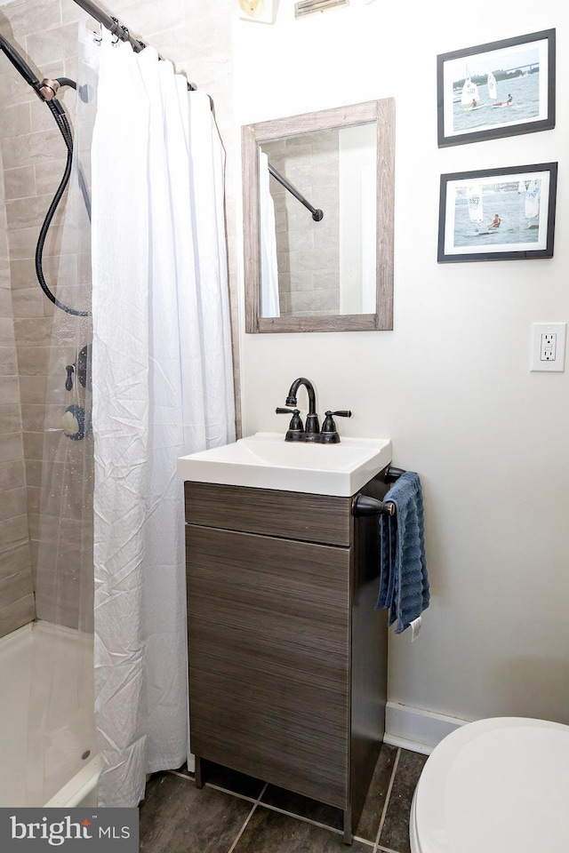 bathroom with vanity, toilet, tile patterned floors, and walk in shower