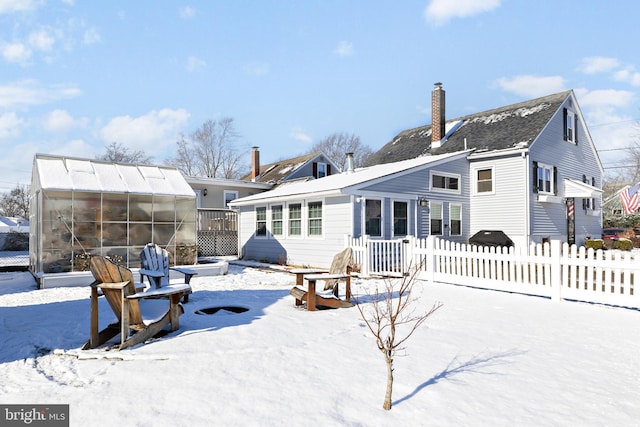 snow covered back of property featuring an outbuilding