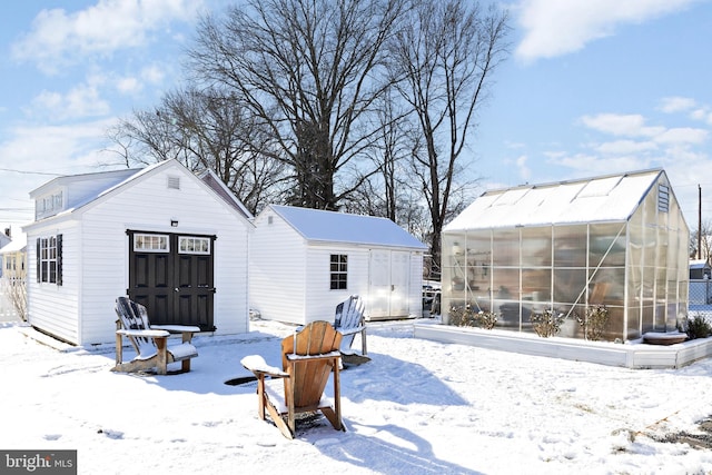 snow covered back of property featuring a shed