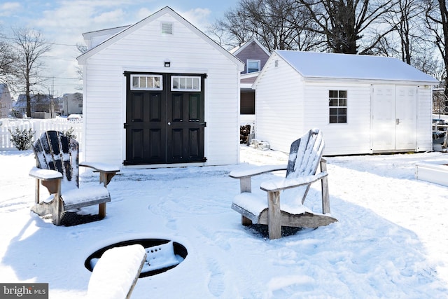 snow covered rear of property featuring an outdoor structure