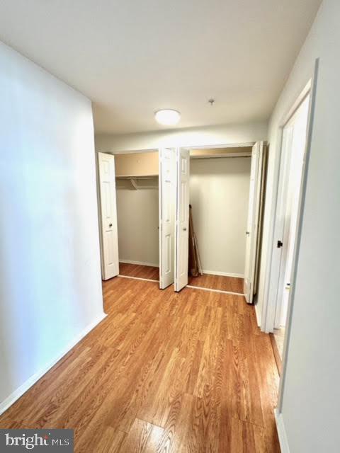 unfurnished bedroom featuring two closets and light hardwood / wood-style flooring