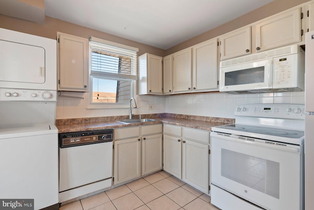 kitchen featuring white appliances, stacked washer and dryer, sink, backsplash, and light tile patterned floors