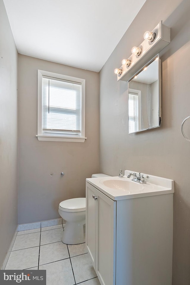 bathroom featuring toilet, a wealth of natural light, tile patterned flooring, and vanity