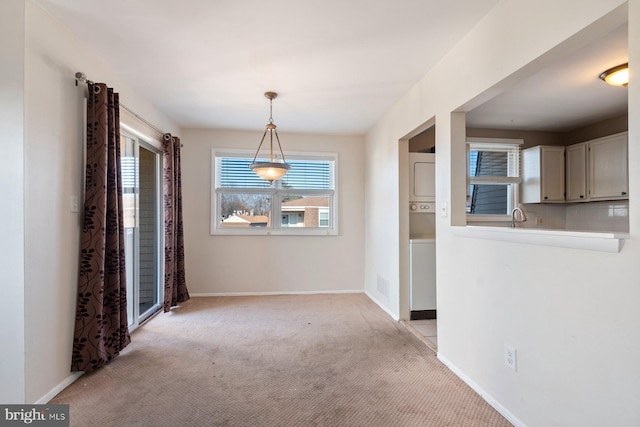 unfurnished dining area featuring light colored carpet and sink