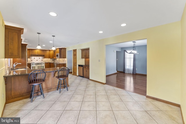 kitchen with decorative backsplash, kitchen peninsula, a notable chandelier, a breakfast bar, and light tile patterned floors