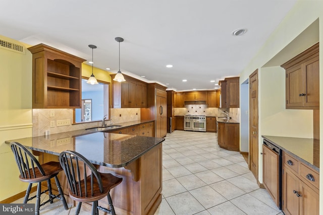 kitchen with pendant lighting, range with two ovens, sink, kitchen peninsula, and a breakfast bar area