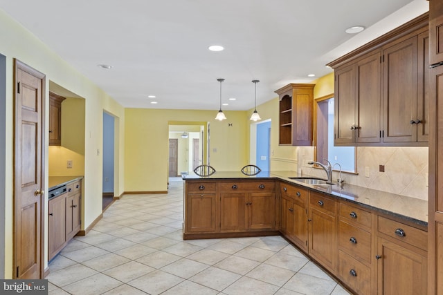 kitchen featuring light tile patterned floors, kitchen peninsula, tasteful backsplash, decorative light fixtures, and sink