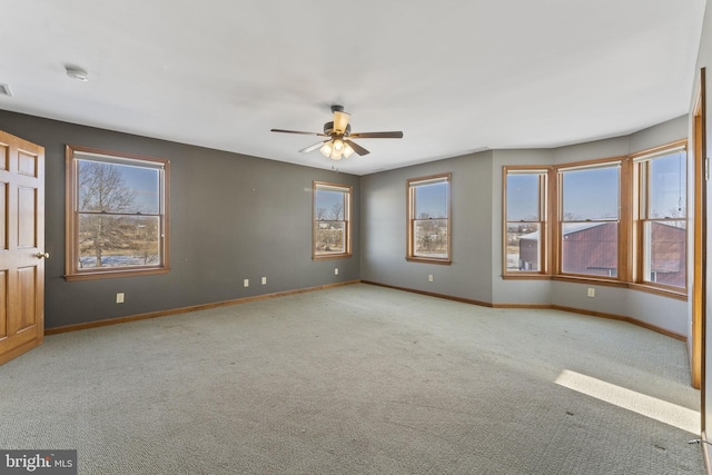 carpeted empty room featuring ceiling fan and plenty of natural light