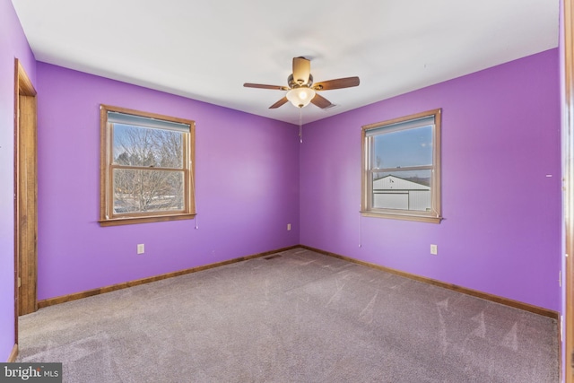 carpeted spare room featuring ceiling fan and a healthy amount of sunlight